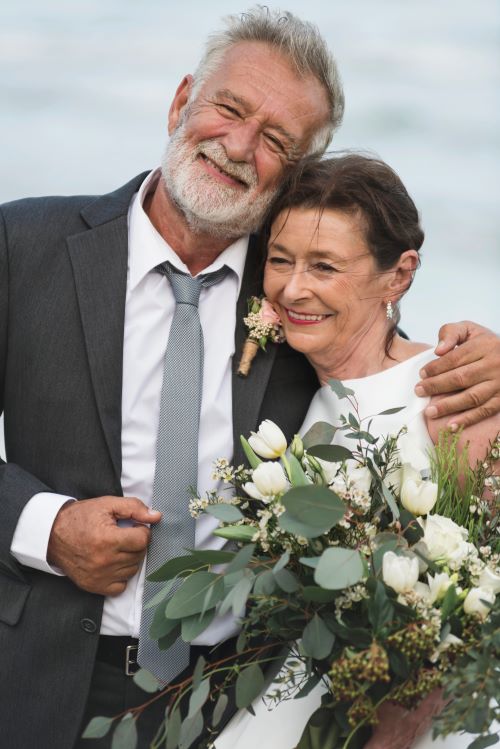 Newly married couple posing on beach after ceremony
